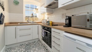 A modern kitchen with white cabinets, a coffee machine, and a window with a view. - Host Stay Portland Apartment (Brighton)