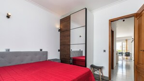 A bedroom with a large bed, a wardrobe, a mirror, and a small stool. - Ory Red Apartment, São Rafael, Albufeira (Albufeira)