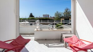A balcony with two red chairs, a beige awning, and a clear view of buildings and greenery in the background. - Ory Red Apartment, São Rafael, Albufeira (Albufeira)