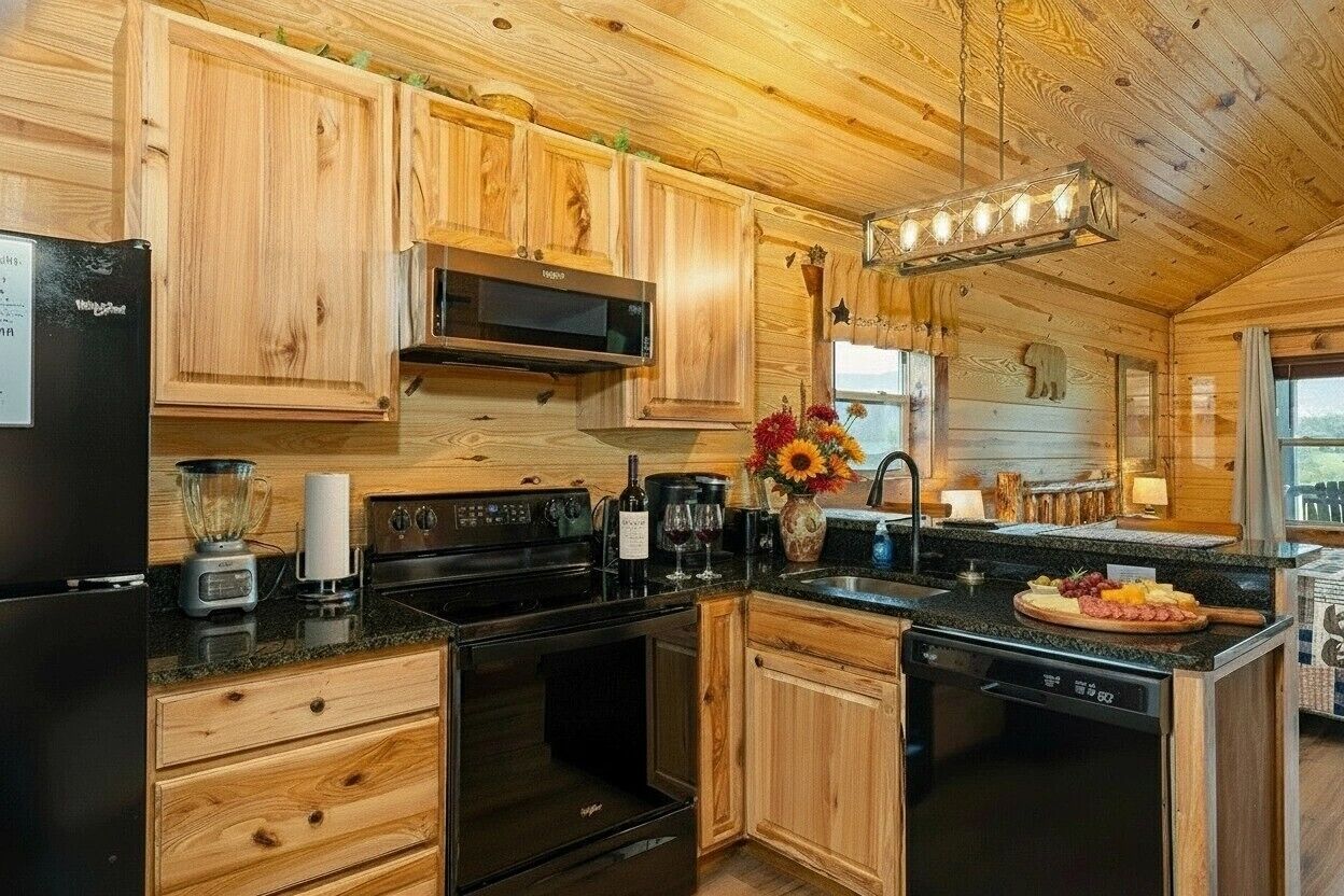 Une cuisine rustique aménagée dans une cabane en bois, comprenant un réfrigérateur, une cuisinière, un four à micro-ondes et des placards en bois.
