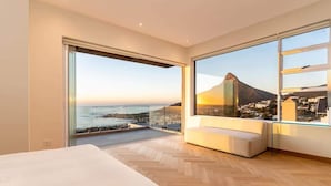 Une chambre moderne dotée d’une grande fenêtre donnant sur un paysage côtier et une montagne.