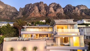 Un immeuble moderne à plusieurs étages, doté d’un patio sur le toit, de grandes fenêtres et offrant une vue sur des montagnes rocheuses.