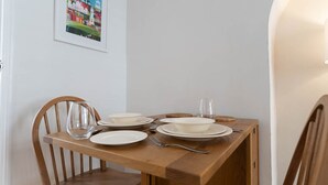 Een houten eettafel gedekt met borden, kommen en bestek.