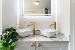 A bathroom with two white sinks, gold faucets, and a marble countertop. - Host Stay Luxe on Margaret Street (Brighton)