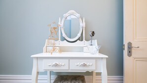 Une coiffeuse blanche avec un miroir, une petite table et un banc.