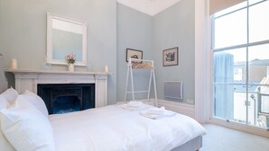 Une chambre à coucher avec un lit, une cheminée, une fenêtre et une échelle.