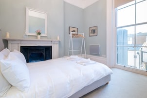 Un dormitorio con cama, chimenea, ventana y escalera.