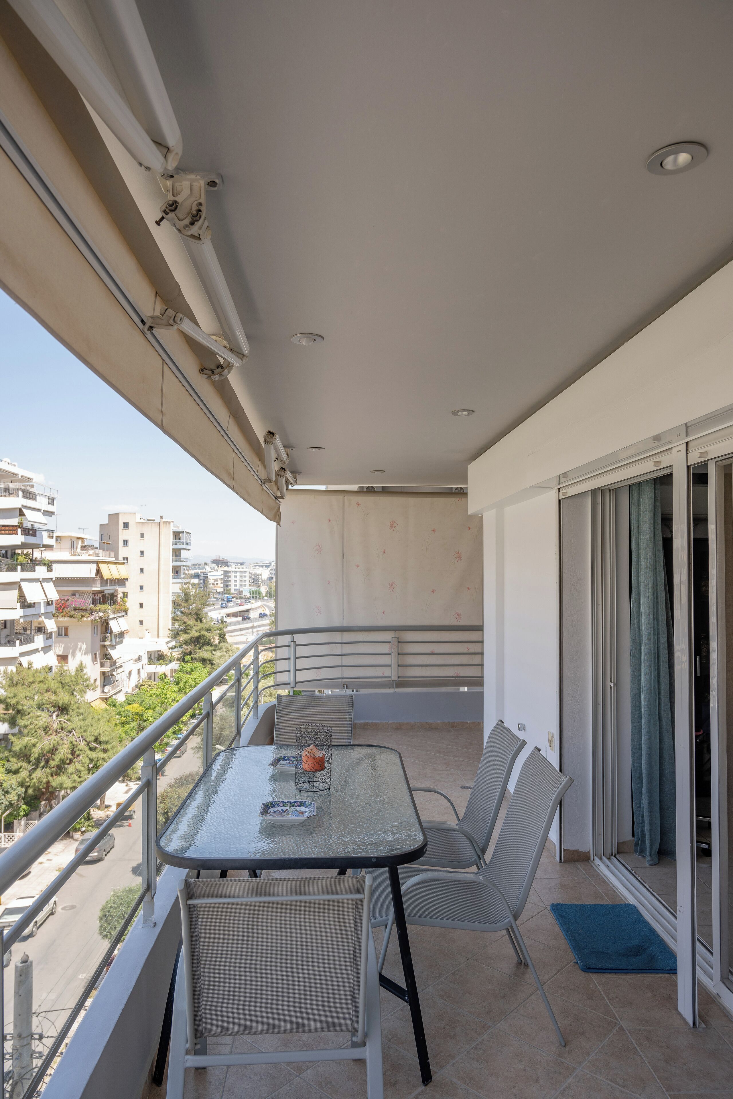 Un balcon avec une table et des chaises, une vue sur la ville et une porte-fenêtre coulissante.