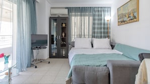 Ein Hotelzimmer mit Bett, Sofa, Fernseher, Schrank und einem Gemälde an der Wand.