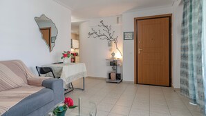Ein Wohnzimmer mit Sofa, einem Tisch mit Blumenvase, einer Wanddekoration und einer Holztür.