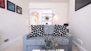 A modern living room with a light blue sofa, black and white polka dot cushions, a glass vase with branches, and a white console table. - Host Stay Guildford Apartment (Brighton)