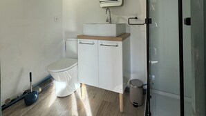 A modern bathroom with a toilet, a sink with a mirror, and a shower area. - Detached house with secure parking  (Vétheuil)