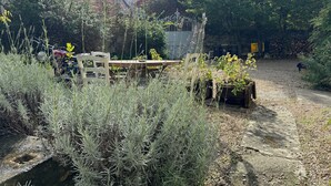 A garden area with a wooden table and chairs, surrounded by various plants and a stone wall. - Detached house with secure parking  (Vétheuil)