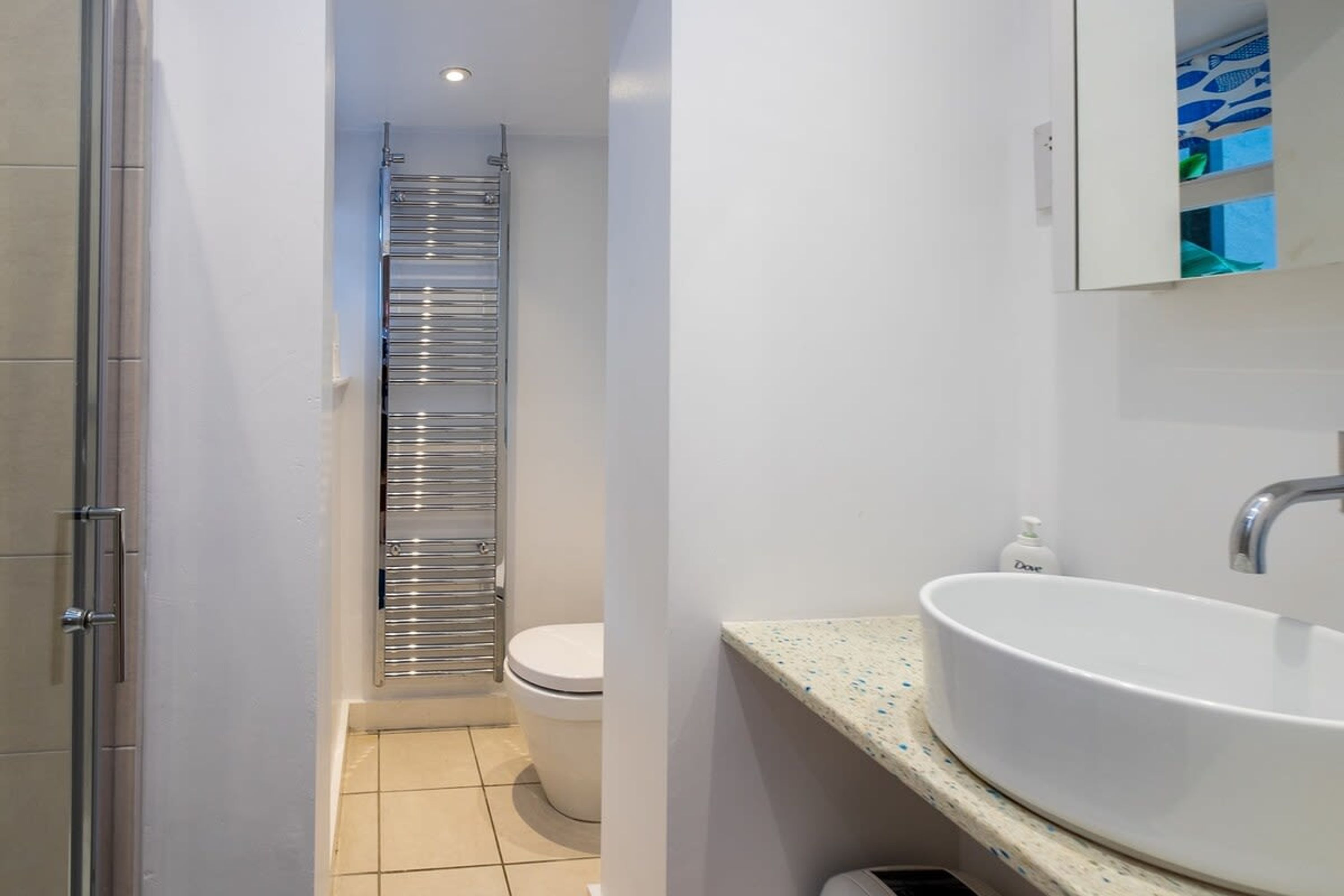 Een moderne badkamer met een witte wasbak, een toilet en een douchecabine van glas.