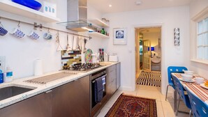 Una cocina moderna con electrodomésticos de acero inoxidable, una alfombra estampada y un comedor con sillas azules.
