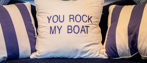 A sofa with striped pillows and a pillow with the text "YOU ROCK MY BOAT".