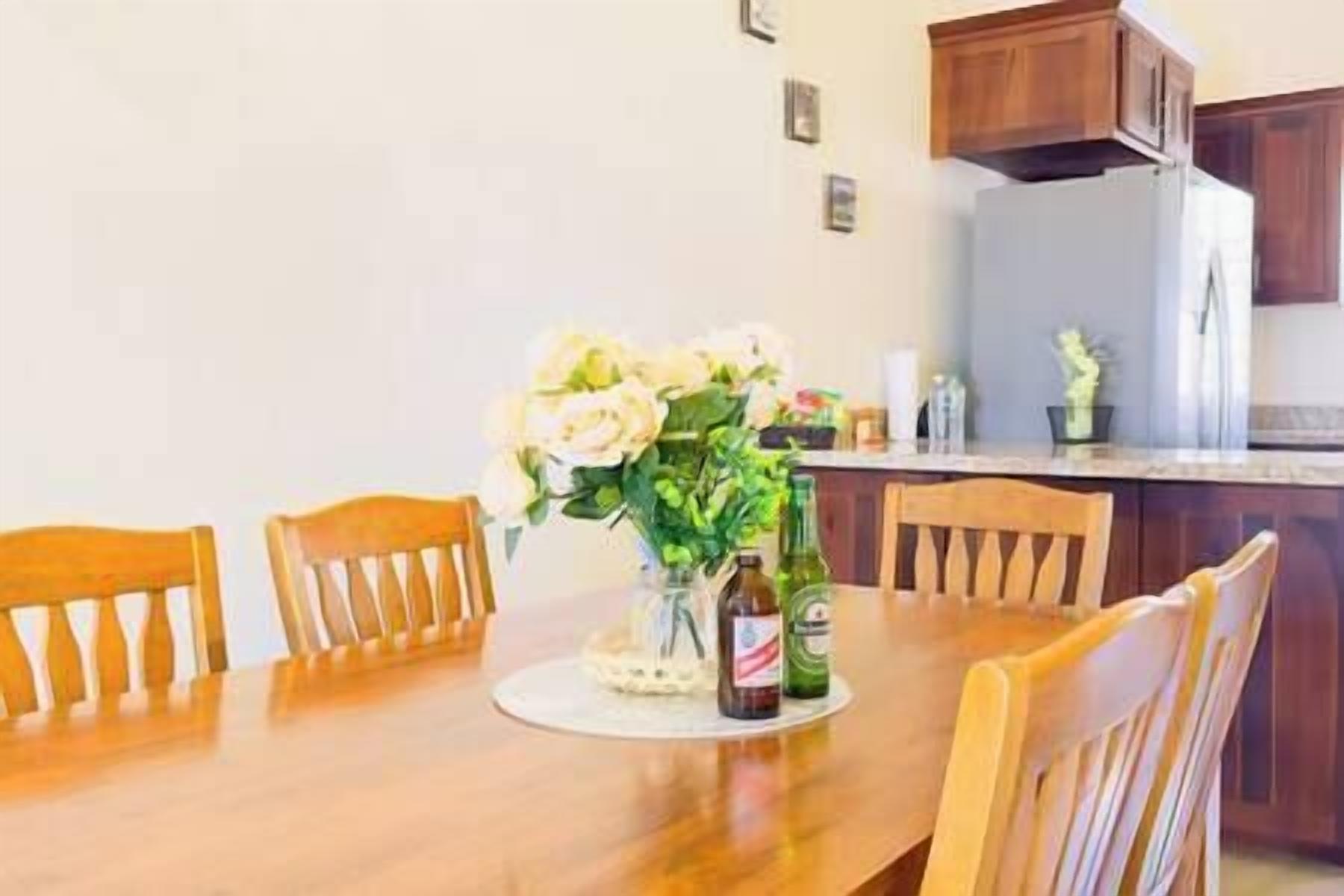 A dining table with chairs, a vase of flowers, and a bottle of beer.
