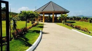 A pavilion with a tiled roof, surrounded by well-maintained grass and palm trees. - Girls Trip ! Stay, Play and Eat $29PP (Falmouth)