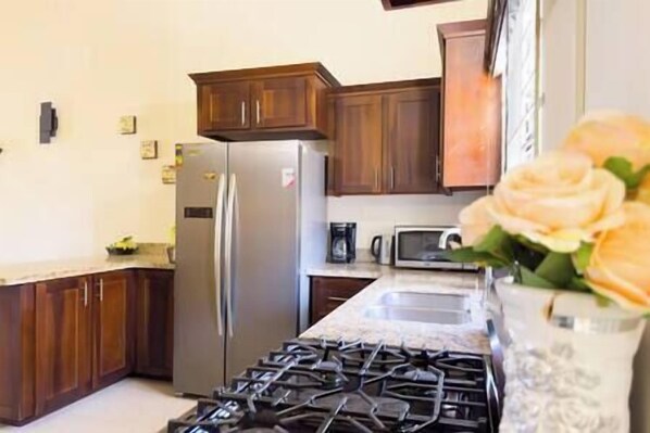 A kitchen with wooden cabinets, a stainless steel refrigerator, a microwave, and a gas stove.