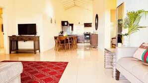 A spacious living area with a dining table, kitchen, and a sofa. - Oceanview couples retreat*pool/raft/beach/shuttle (Falmouth)