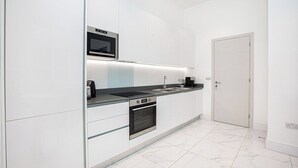 A modern kitchen with white cabinetry, a built-in oven, a microwave, and a sink.