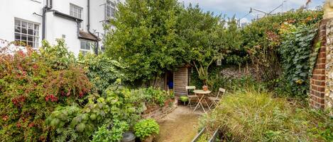 A garden with a variety of plants and a small table with chairs.