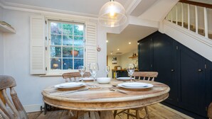 A dining area with a round wooden table set for four, surrounded by wooden chairs. - Host Stay The September Cottage (Brighton)