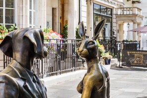 Une statue de bronze représentant un chien et un lapin, située dans une rue de la ville.