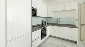 Een moderne keuken met witte kasten, een zwart aanrecht, een ingebouwde oven en een roestvrijstalen spoelbak.