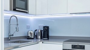 A modern kitchen with a built-in microwave, a kettle, a toaster, and an oven. - Modern Flat, Steps from Oxford Street! (London)