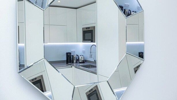 A hexagonal mirror reflecting a modern kitchen with a microwave, coffee maker, and toaster. - Modern Flat, Steps from Oxford Street! (London)