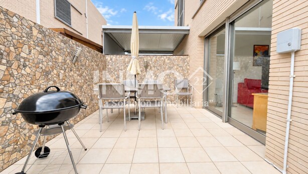Une terrasse avec un barbecue, des sièges d’extérieur et un mur en pierre.