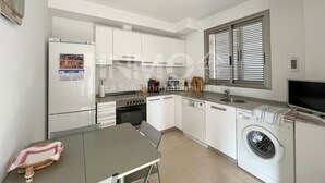 Een compacte keuken met een koelkast, fornuis, oven, vaatwasser en een wasmachine.