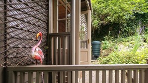 A wooden deck with a metal fence, a door, and a green water tank in the background. - Host Stay The Eco Cabin (Brighton)