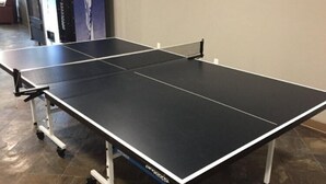 Una mesa de ping pong con red en una habitación con suelo de baldosas.