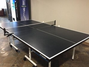 A ping pong table with a net in a room with a tiled floor.