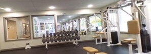 A gym with exercise equipment, mirrors, and a bench.