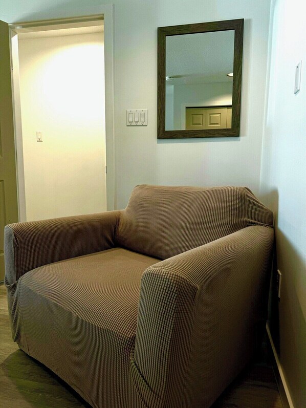 Un canapé une place, à motifs à carreaux, placé contre un mur, avec un miroir au-dessus.