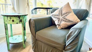 Una silla con un cojín y una mesita auxiliar cerca.