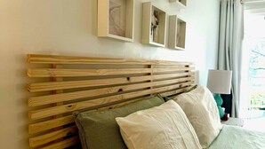 Una cama con cabecera de madera, varias almohadas y colcha estampada verde.