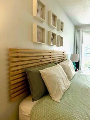 A bed with a wooden headboard, multiple pillows, and a green patterned bedspread.