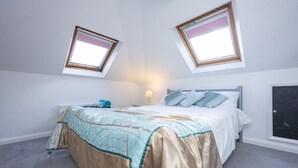 A bedroom with a bed, two skylights, a nightstand, and a lamp. - Host Stay Downs Valley House (Brighton)