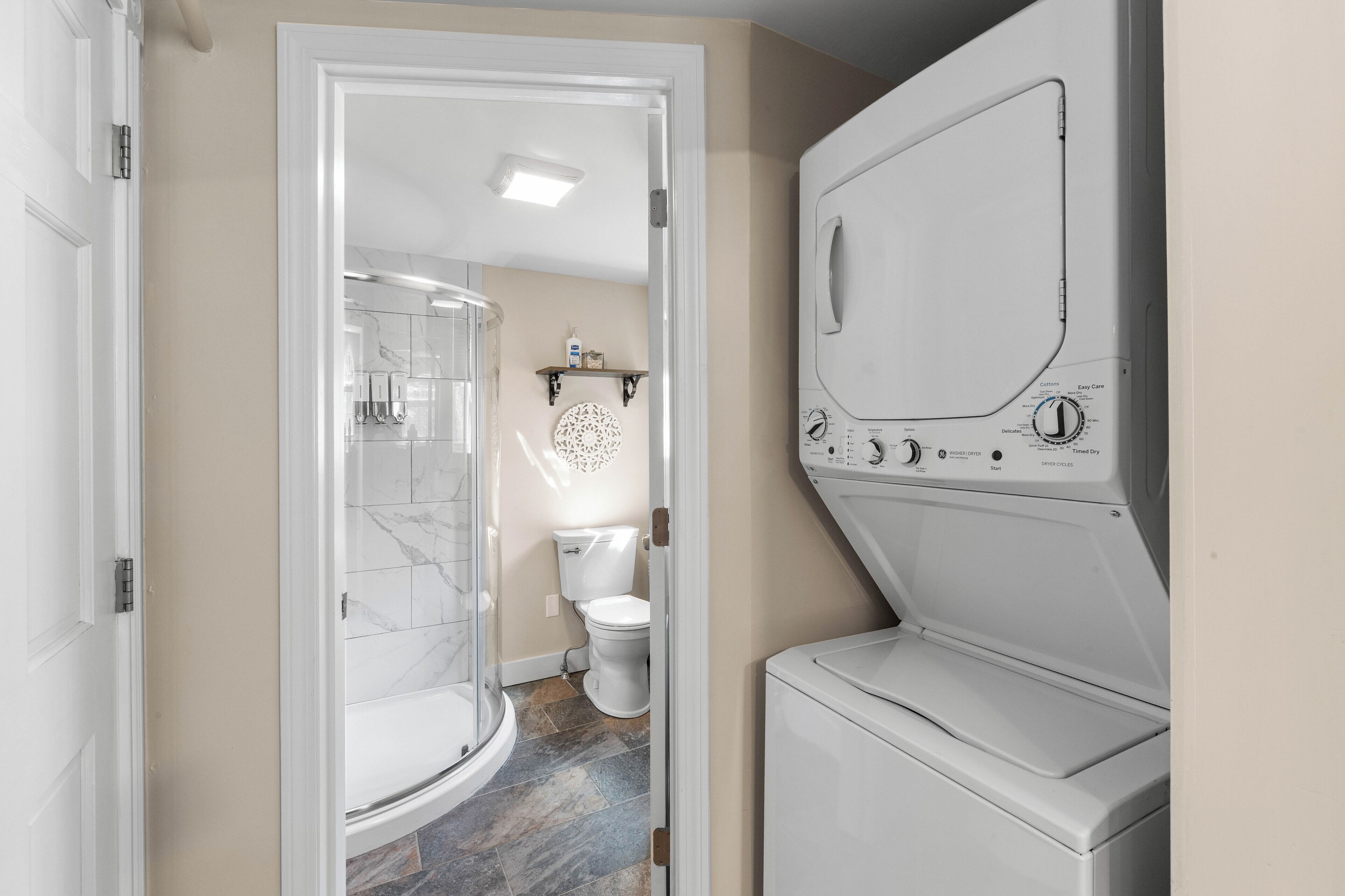 A laundry room with a washing machine, a dryer, and a shower.