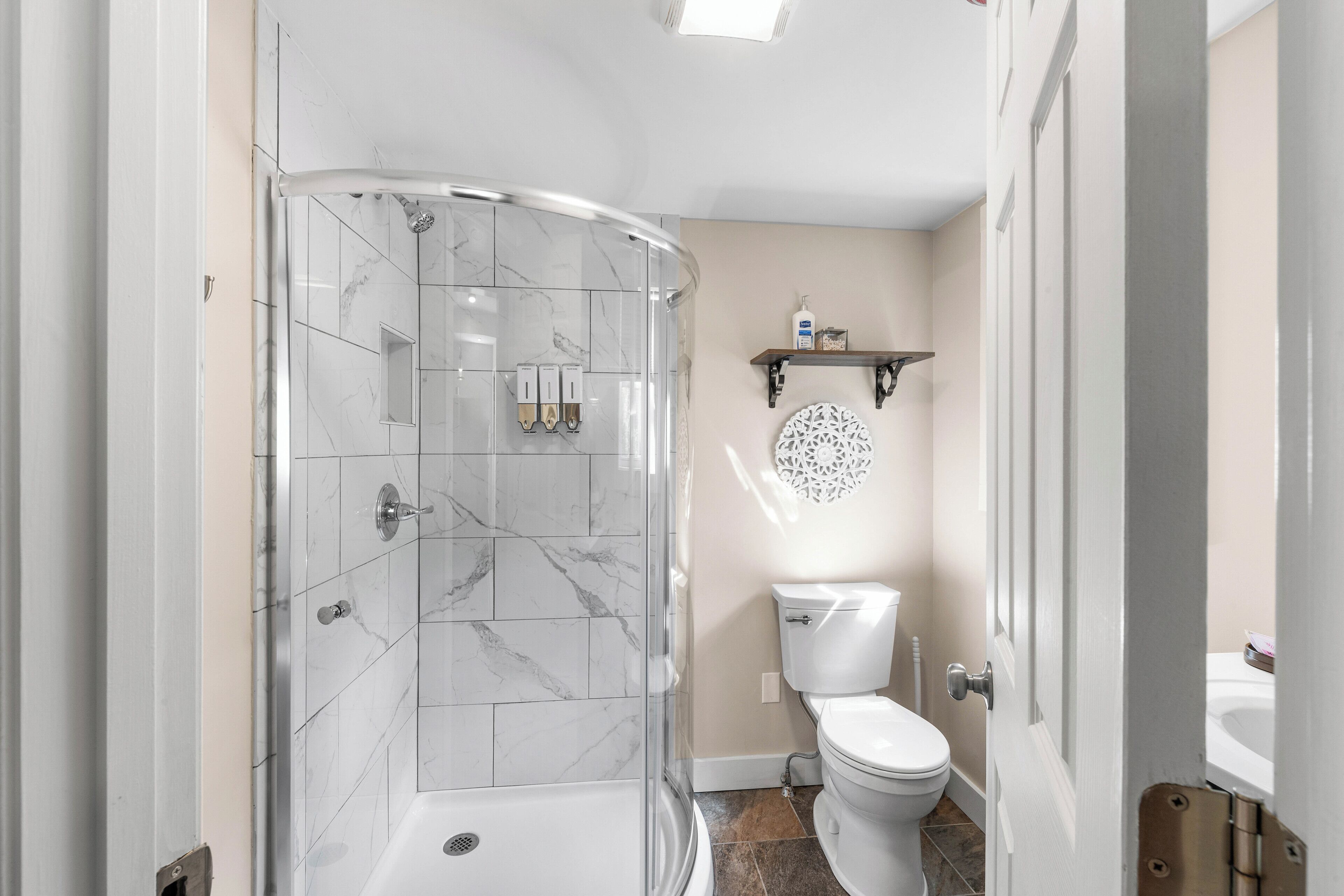A bathroom with a glass-enclosed shower, a toilet, and a sink.