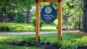 A wooden sign with a logo and text for Tuckaway Suites at East Branch, 372 NH Route 15A. - TuckAway Suites at East Branch (Intervale)