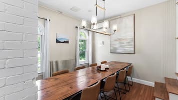 A dining area with a long wooden table, six chairs, a chandelier, and a large abstract painting on the wall.
