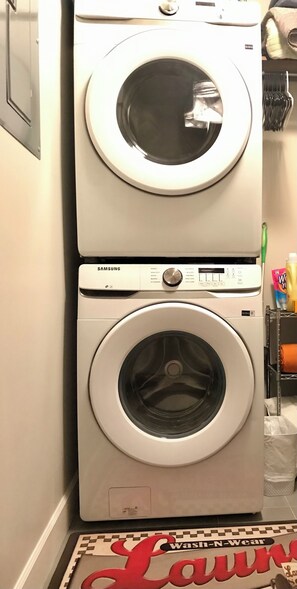 Convenient laundry facility with two front-loading washing machines and a shelf for essentials.