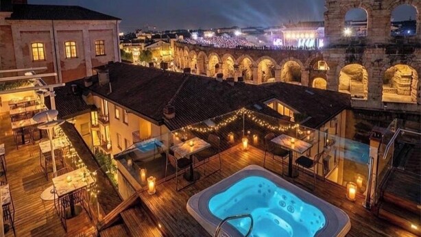 A rooftop pool area with a hot tub, outdoor seating, and a view of ancient ruins at night. - ARENA AROUND - IMPERIAL SUITE (Verona)