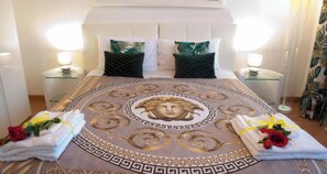 Una habitación de hotel con una cama grande, dos mesitas de noche y un cabecero decorativo.