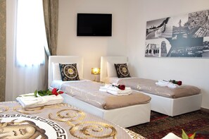 Camera d'albergo con due letti, una TV a schermo piatto e un quadro appeso al muro.